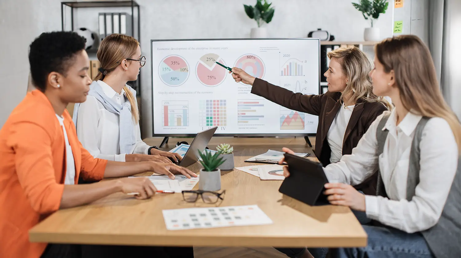 4 business people working on data charts in a meeting.