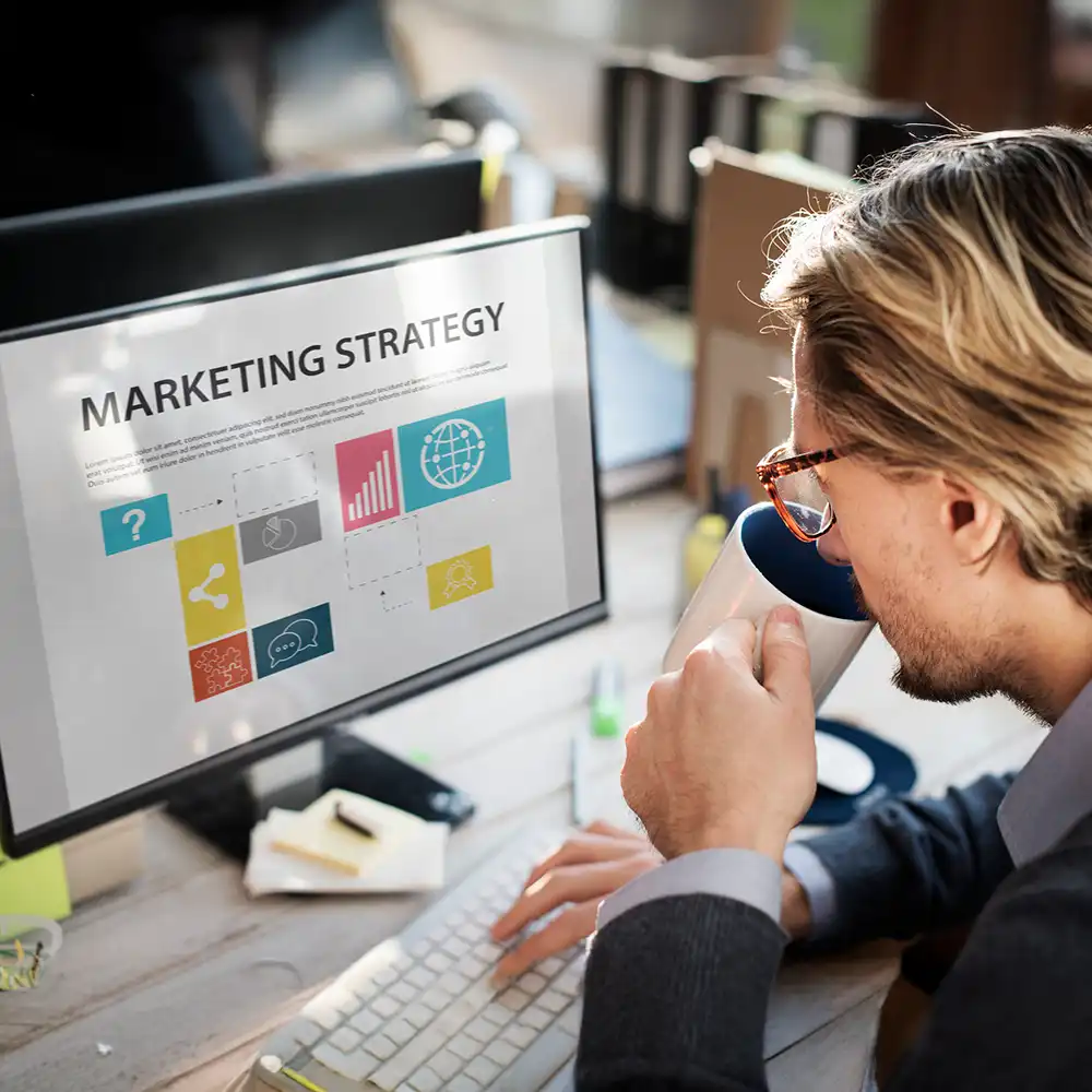 A man working on his laptop displaying the word " marketing strategy "